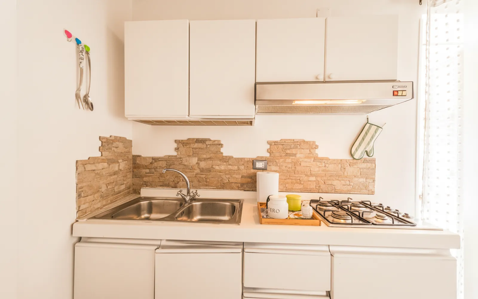 Il lavello e il piano cottura a gas della cucina, con il rivestimento in pietra