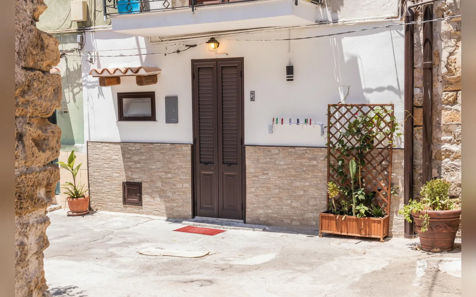 La facciata della casa al piano terra, con la porta in legno, il graticcio e le piante