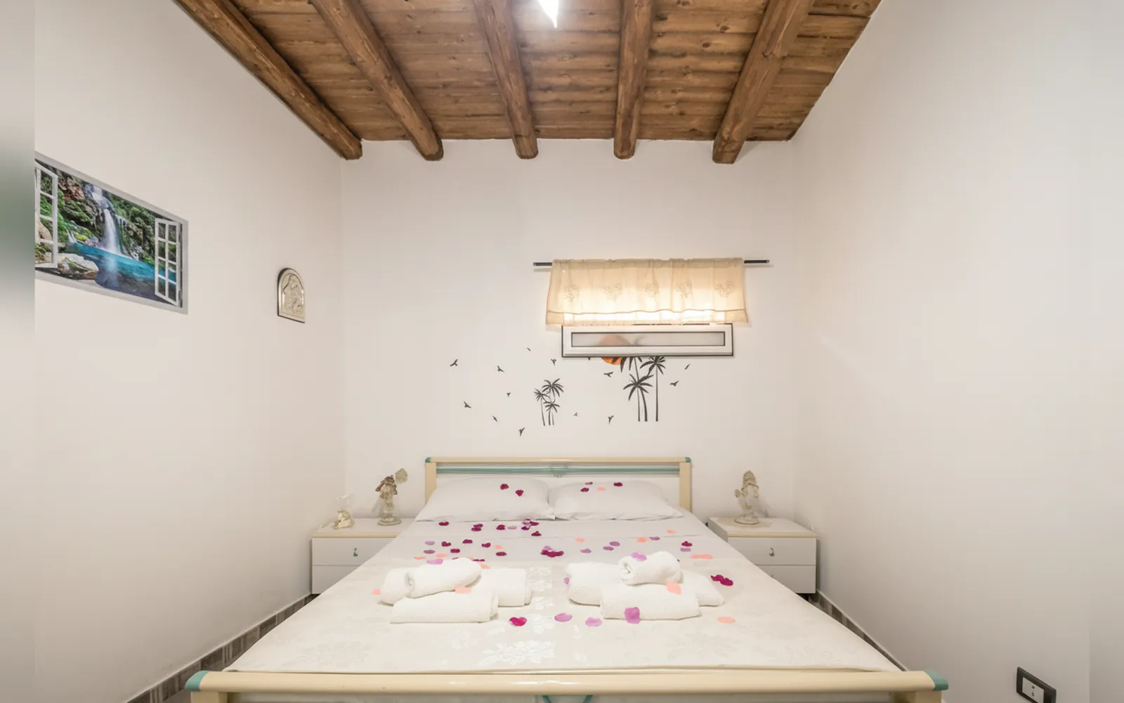 Il letto matrimoniale con i petali e gli asciugamani piegati, sotto la finestra decorata