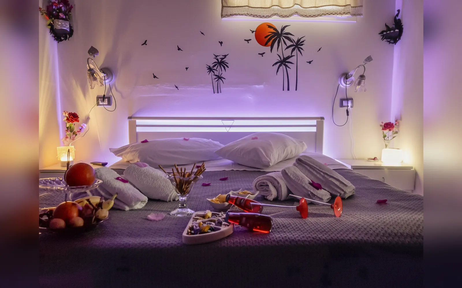 La camera la sera, con le luci soffuse, il letto preparato e un vassoio di frutta