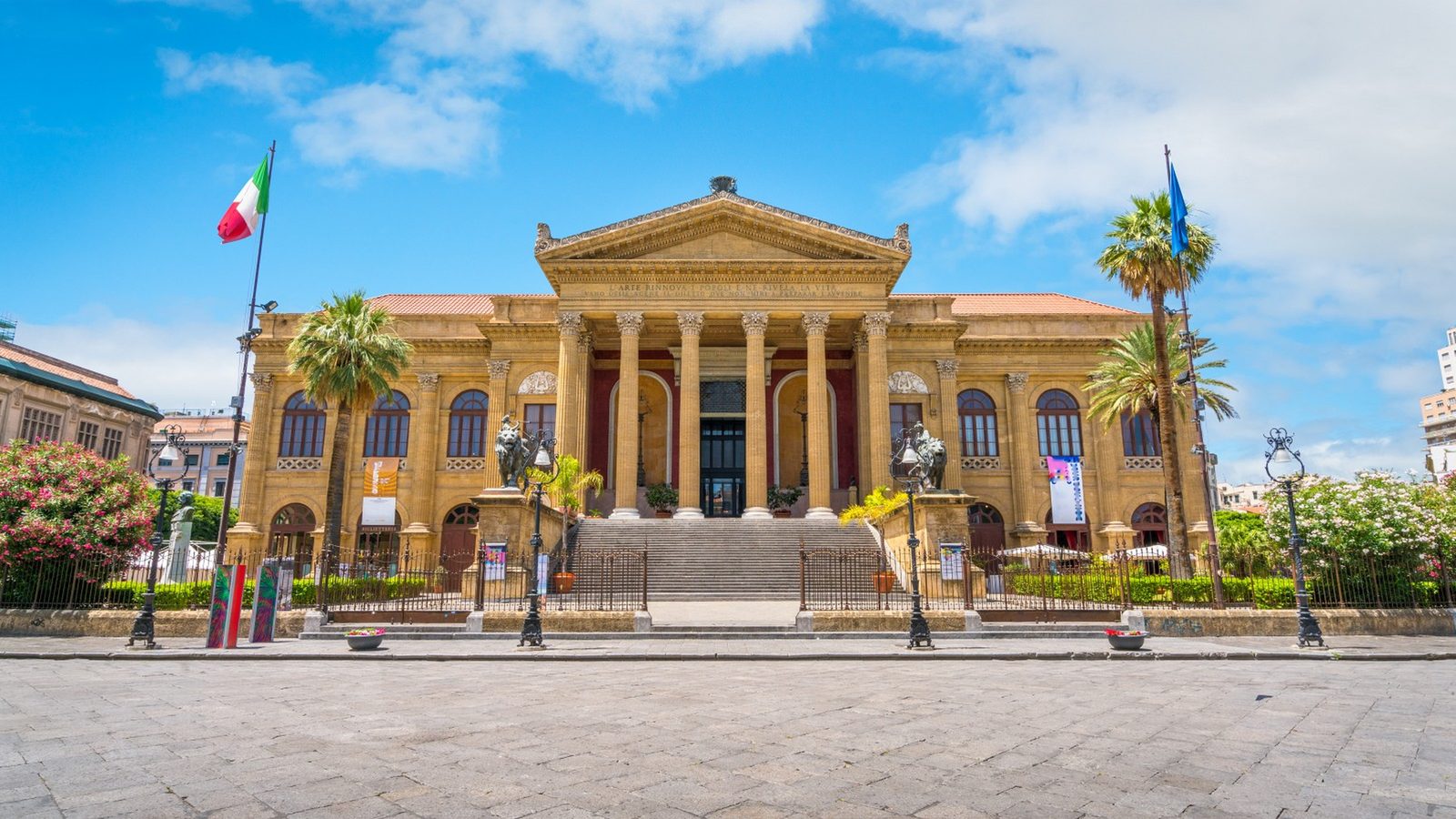 La facciata del Teatro Massimo con la scalinata, il colonnato e le palme, in una giornata di sole